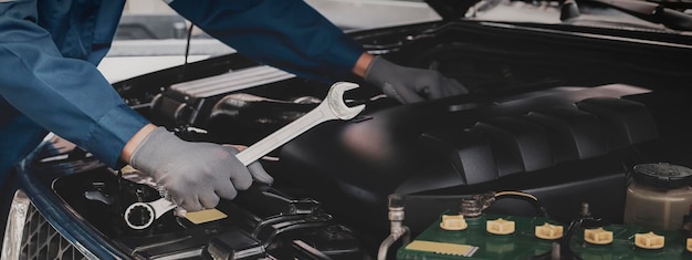 Le mécanicien travaille sur le moteur de la voiture dans le garageConcept de service d'inspection automobile