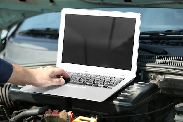 Photo mécanicien utilisant des diagnostics informatiques lors de la réparation d'une voiture