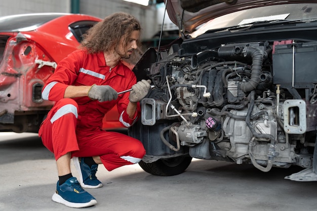 Un mécanicien utilise une clé pour serrer le moteur d'une voiture dans un garage automobile