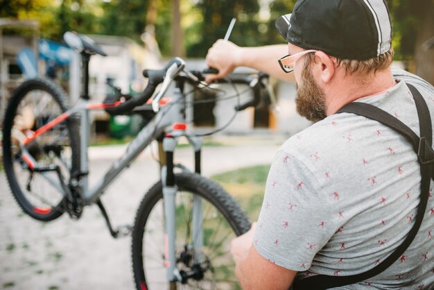 Mécanicien de vélo dans le tablier ajuste le vélo en plein air