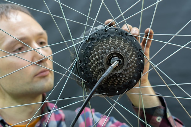 Un mécanicien de vélos tient une roue d'un vélo Réparation de vélos Rayons de roue et cassette d'un vélo de montagne sur fond noir