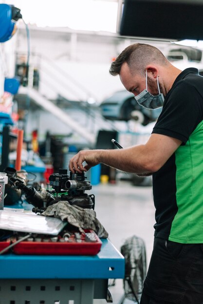 Photo mécanicien vérifiant des pièces de voiture dans l'atelier