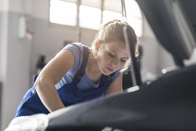 Une mécanicienne confiante qui répare une voiture dans l'atelier de réparation automobile