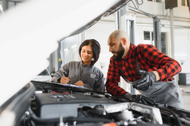 Photo mécaniciens masculins et féminins travaillant sur la voiture