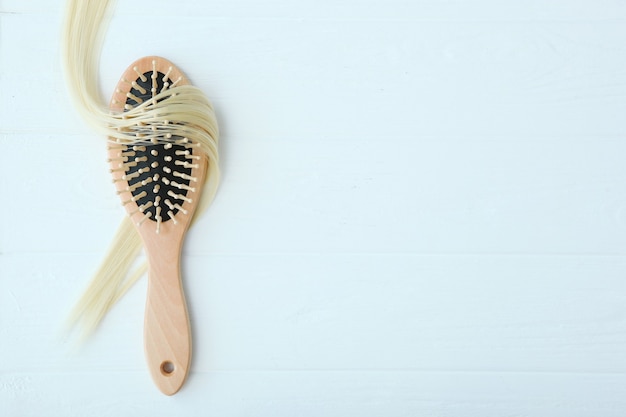 Une mèche de produits de soins capillaires pour cheveux blonds et un peigne sur fond coloré