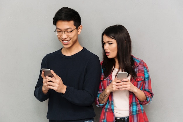 Mécontent jeune femme asiatique bavardant par téléphone mobile.