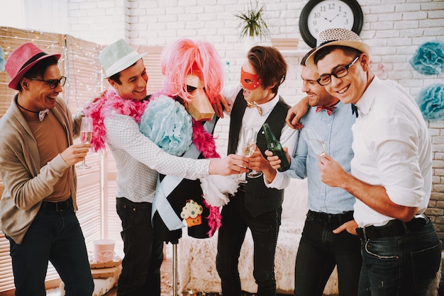 Des mecs gays en nœuds papillons tinter des verres de champagne à la fête