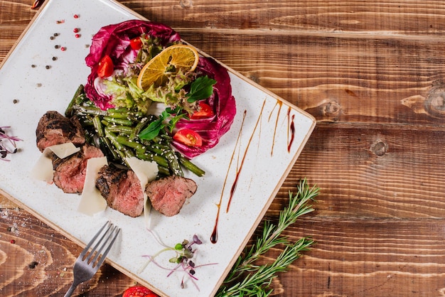 Médaillons de viande saignants moyens avec des légumes sur le fond en bois