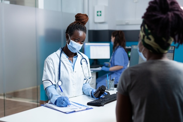 Médecin afro-américain écrivant un traitement médicamenteux sur le presse-papiers