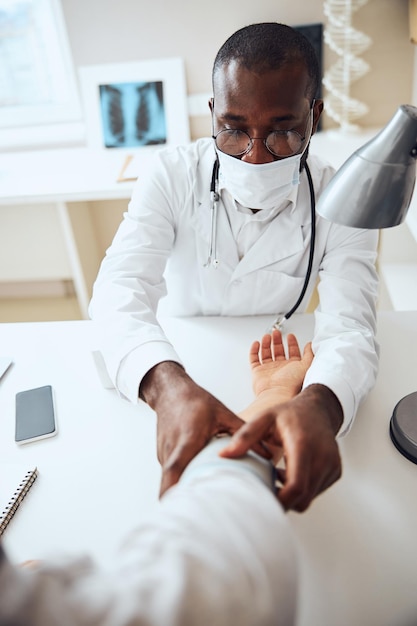 Médecin afro-américain fixant un brassard de tension artérielle sur une main