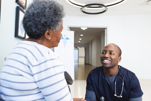 Photo un médecin afro-américain heureux parlant avec une femme âgée dans la salle d'attente de l'hôpital.