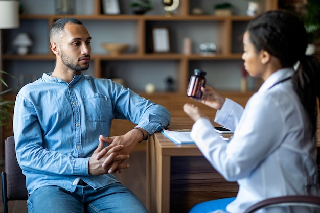 Médecin afro-américain montrant des médicaments à un patient noir