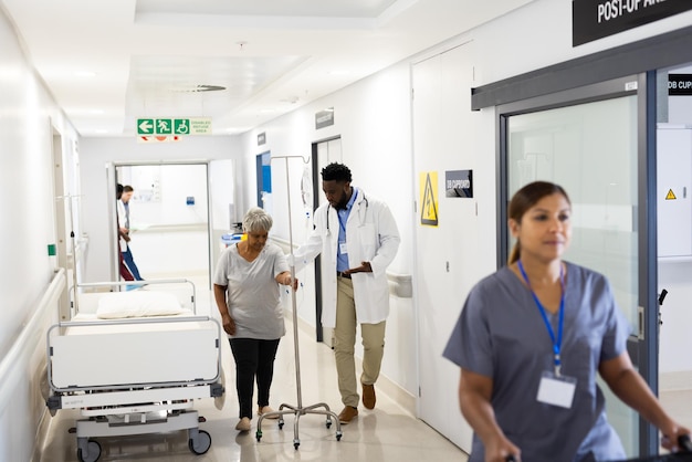 Photo un médecin afro-américain en train de parler à une patiente âgée avec une goutte à goutte qui marche dans le couloir.