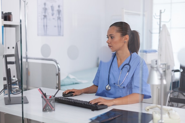 Médecin à l'aide d'un ordinateur au bureau de l'hôpital. Médecin de santé utilisant l'ordinateur dans une clinique moderne regardant le moniteur, la médecine, la profession, les gommages.