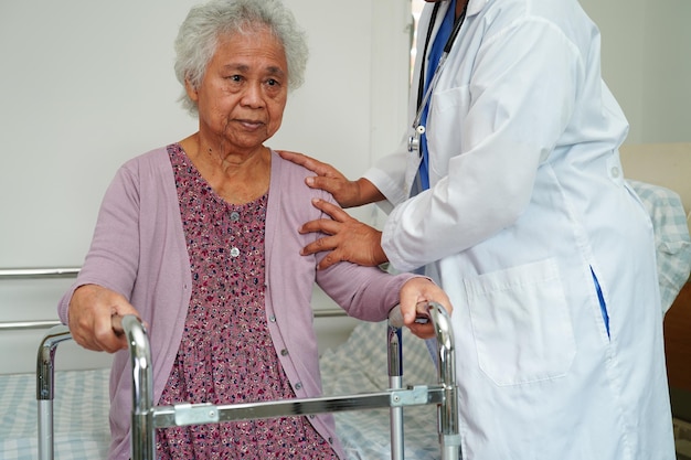 Un médecin aide une patiente asiatique âgée handicapée à marcher avec une marchette dans le concept médical de l'hôpital infirmier