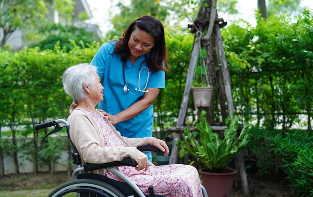 Un médecin aide une patiente handicapée asiatique âgée assise sur un fauteuil roulant dans le concept médical du parc