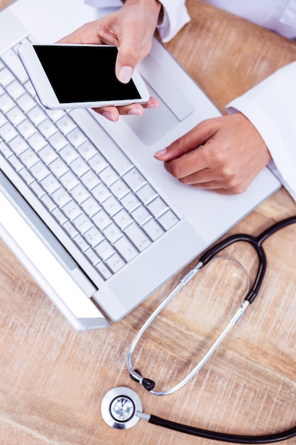 Médecin à l&#39;aide de smartphone sur le bureau en bois