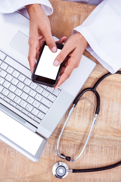 Médecin à l&#39;aide de smartphone sur le bureau en bois