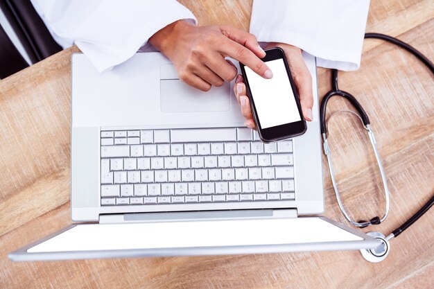 Médecin à l&#39;aide de smartphone sur le bureau en bois