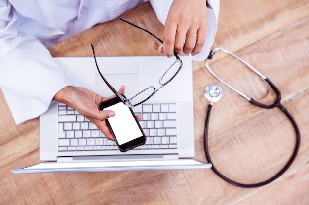 Photo médecin à l'aide de smartphone sur le bureau en bois