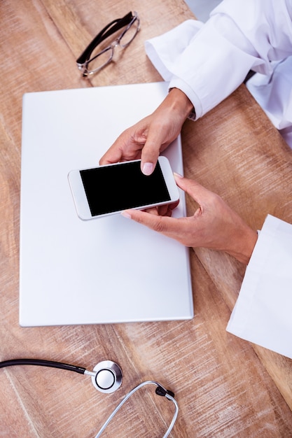 Médecin à l&#39;aide de smartphone sur le bureau en bois