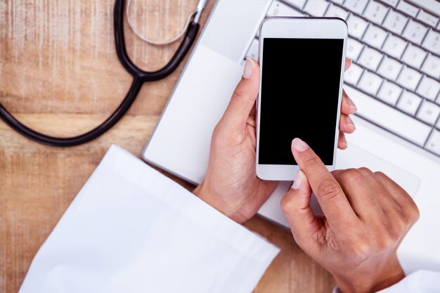 Médecin à l&#39;aide de smartphone sur le bureau en bois