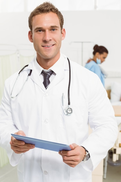 Photo médecin à l'aide de tablette numérique avec des collègues et des patients derrière