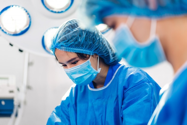 Médecin anesthésiologiste professionnel équipe médicale et assistant préparant le patient à la chirurgie gynécologique effectuant des opérations avec du matériel de chirurgie dans une salle d'urgence de l'hôpital moderne