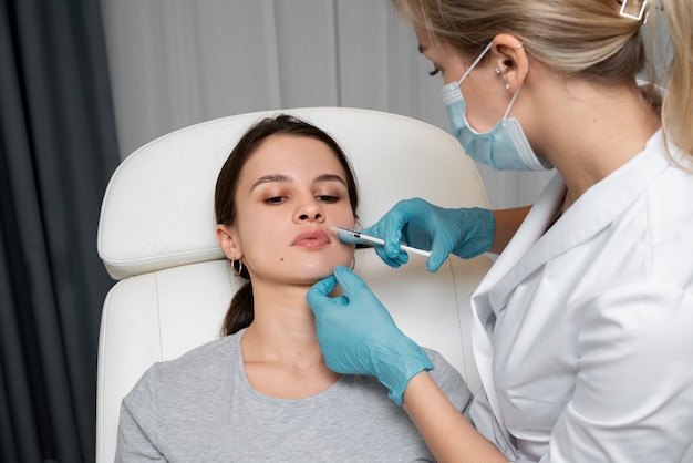 Photo médecin à angle élevé donnant des remplisseurs de lèvres à une femme