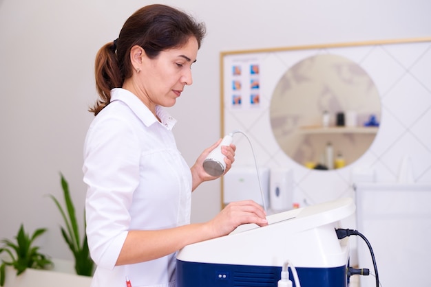 Un médecin avec un appareil de cavitation dans une clinique de cosmétologie.