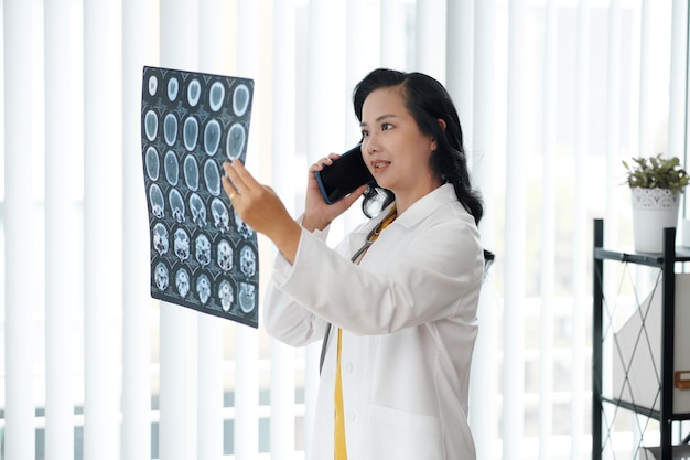 Photo médecin appelant un radiologue pour discuter de la radiographie des disques de la colonne vertébrale