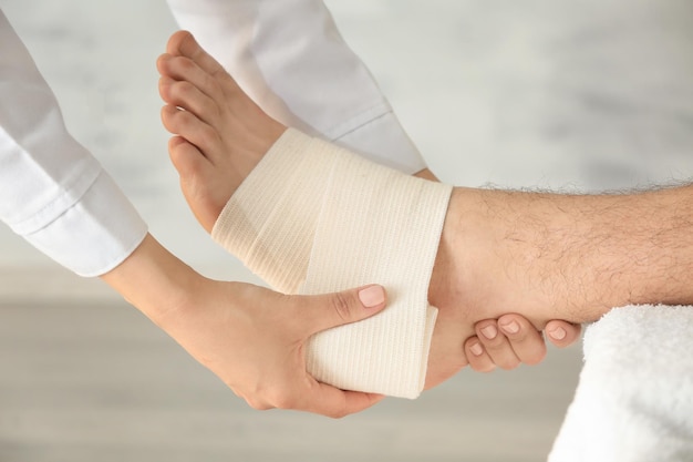 Médecin appliquant un bandage sur la jambe du patient en gros plan de la clinique