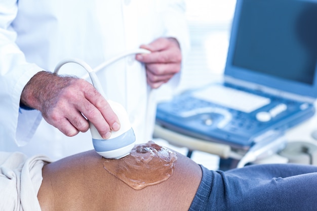 Médecin appliquant le gel sur le ventre de la femme enceinte