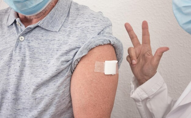 Un médecin après avoir injecté à un homme de 70 ans la troisième dose du vaccin contre le coronavirus covid-19 montre le numéro trois avec sa main. Concept de protection et de soins de santé