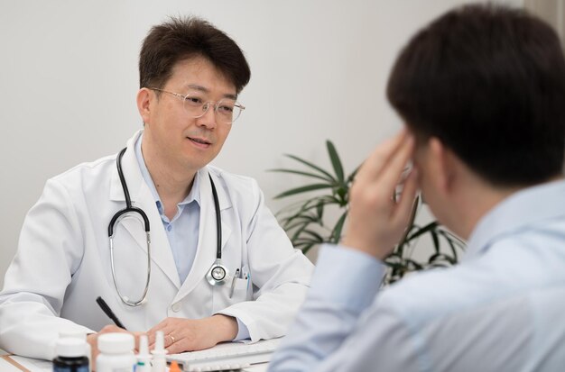 Photo un médecin asiatique d'âge moyen et un patient subissant un traitement thérapeutique dans un hôpital