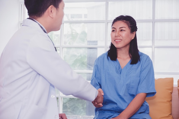 Un médecin asiatique de l'équipe se serre la main d'un patient de traitement d'accord à l'hôpital