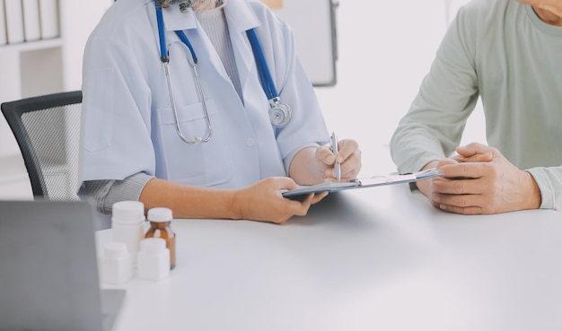 Un médecin asiatique mature parle à son patient en expliquant la procédure à une vieille dame.