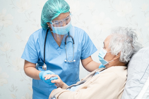 Médecin Asiatique Portant Un écran Facial Et Une Combinaison Epi Pour Vérifier Le Patient