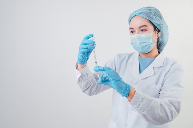 Médecin asiatique regardant et préparant le vaccin à seringue et le flacon pour injection à un patient malade sur fond blanc. Le personnel médical et le concept de technologie de prévention des maladies. Thème de l'épidémie de coronavirus