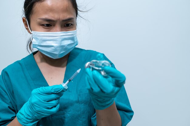 Médecin asiatique avec seringue et vaccin pour protéger le virus covid19 sur fond blanc