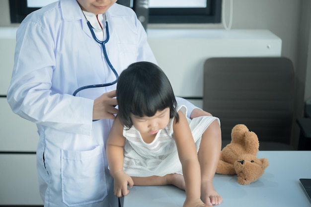 Médecin asiatique utilisant un stéthoscope pour vérifier sa respiration et le cœur d'une jolie fille vérifier la santé des enfantsThaïlandais