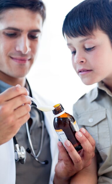 Médecin assertif donnant des médicaments à un petit garçon