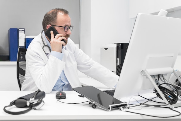 Médecin au bureau parlant au téléphone