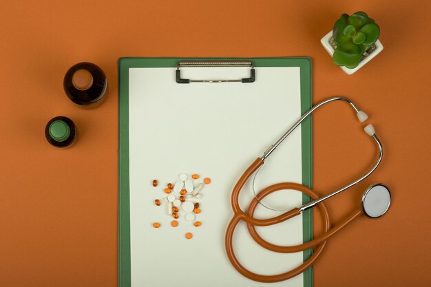 Médecin Au Travail Stéthoscope Orange Pilules Bouteilles Médicales Et Presse-papiers Vide Sur Fond Orange