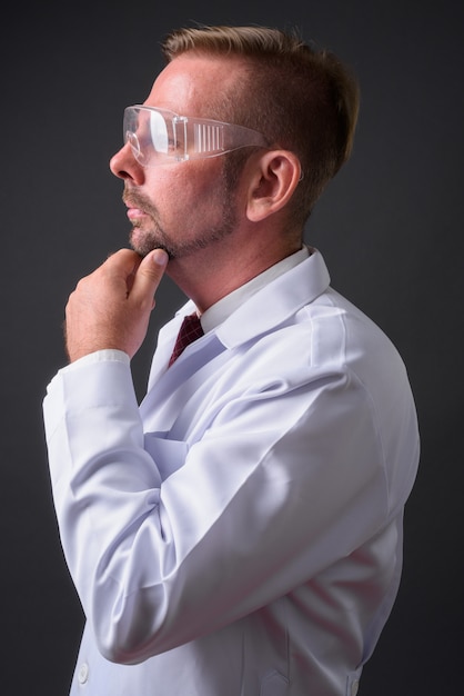 Médecin barbu blond avec barbiche contre mur gris