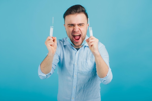 médecin barbu et tenant une seringue et criant sur fond bleu