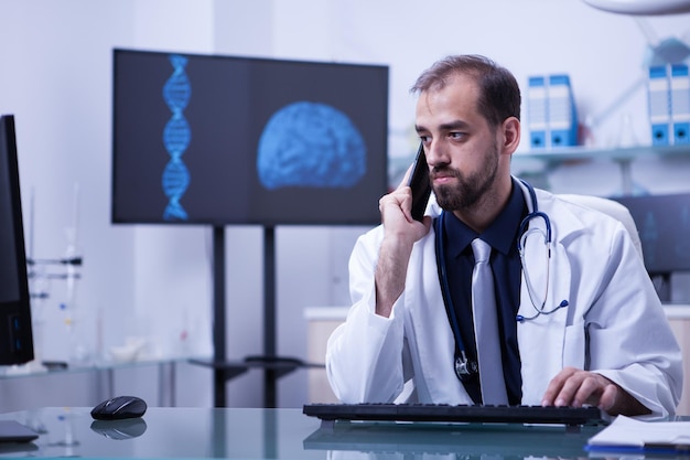 Médecin en blouse blanche ayant un appel téléphonique au cabinet de l'hôpital. Médecin utilisant la technologie moderne.