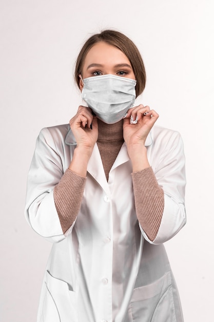 Un médecin en blouse blanche montre comment porter un masque médical