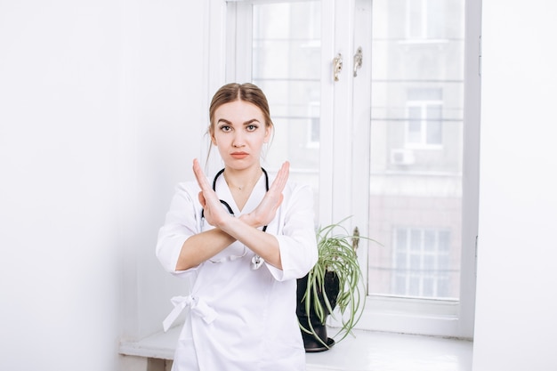 médecin en blouse blanche avec un stéthoscope sur fond de fenêtre dans un bureau lumineux