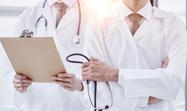 Un médecin en blouse blanche et un stéthoscope se tient les bras croisés